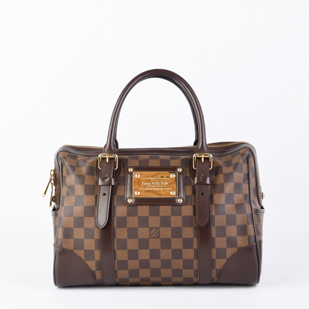 Berkeley er en elegant og strukturert håndveske fra Louis Vuitton, laget i slitesterk Damier Ebene canvas med detaljer i mørkebrunt skinn og gullfarget metallplate foran. Produsert i Frankrike i 2009, og kommer med alle originale deler.